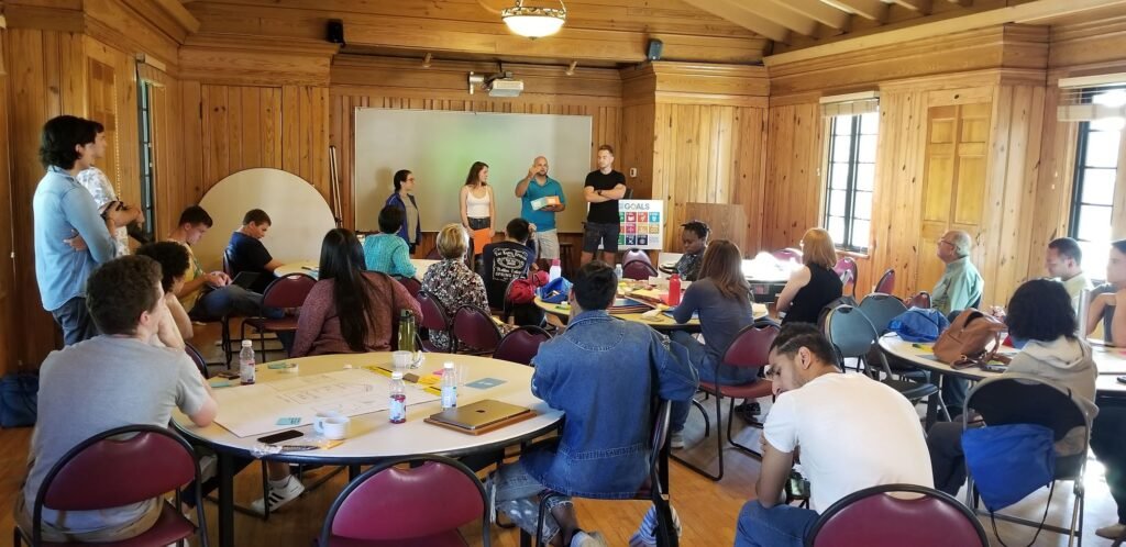 Participants engage in a facilitated workshop with small-group tables and Sustainable Development Goal materials.